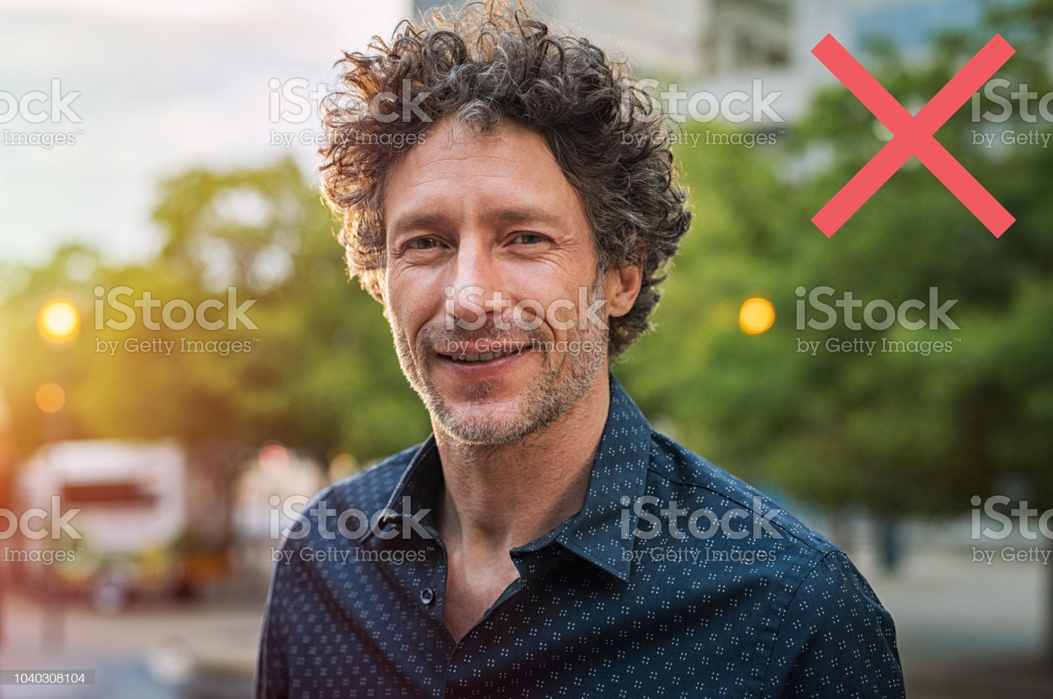 stock-photo-donts Portrait of happy mature man looking at camera outdoor. Senior businessman with beard feeling confident at sunset. Closeup face of business man smiling with city in background.